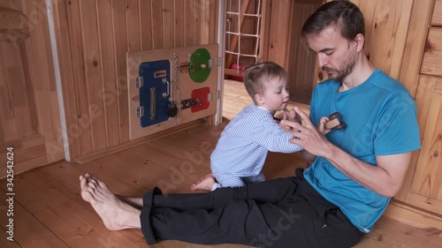 Multitasking father work from home and play with kid. Lifestyle dad trying work on smartphone and his child distracts him, drawing attention. Remote home office with child.