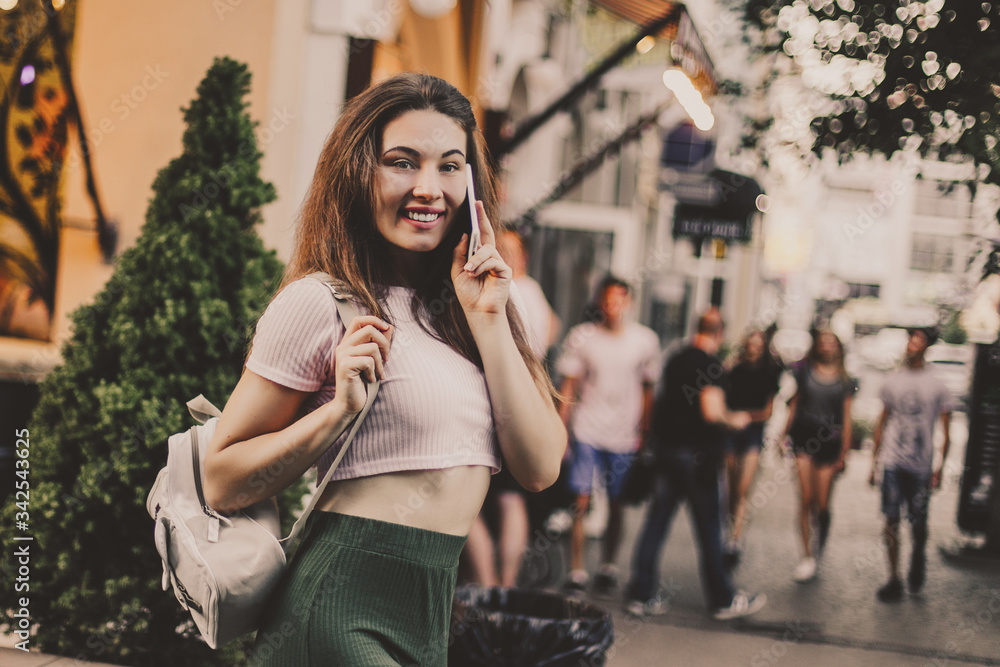 Smiling woman using phone and drink coffee on the street in summer day. Smiling woman using phone and drink coffee on the street in summer day.