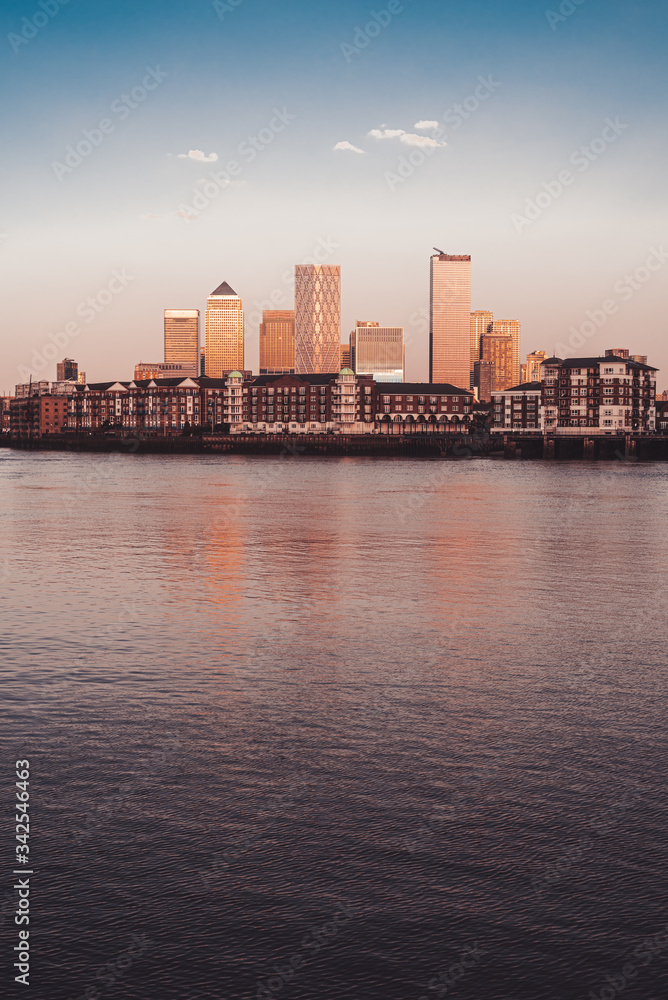 Canary wharf banking center by the majestic river at sunset with old buildings London Vertical