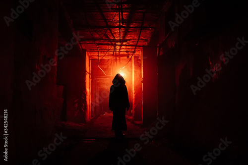 Creepy silhouette in the dark red illuminated abandoned building. Horror about maniac concept