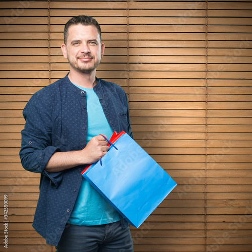 Young man wearing a blue outfit. Holding shopping bags.