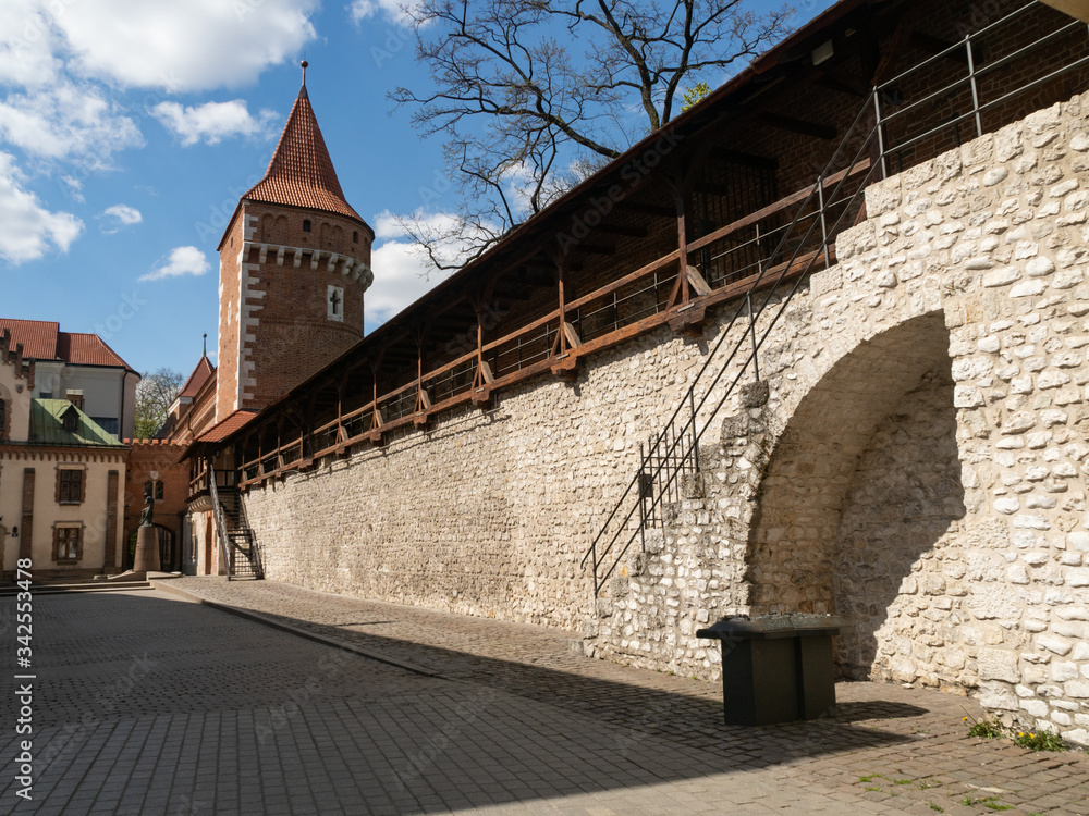 Old town medieval walls and Pijarska street. Usually lively corner with outdoor art market, now empty due to the coronavirus pandemic. Old town medieval walls and Pijarska street. Usually lively corner with outdoor art market, now empty due to the coronavirus pandemic.