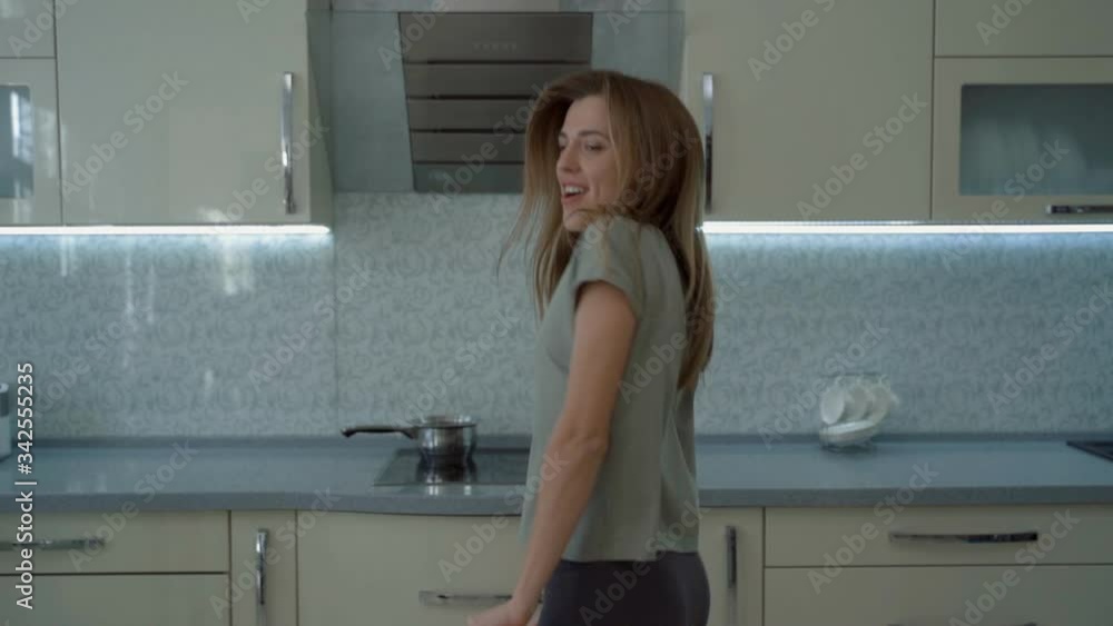 Energetic dancing of a happy girl. Pretty young woman dancing in kitchen and listening music. Beautiful woman listening to music Energetic dancing of a happy girl. Pretty young woman dancing in kitchen and listening music. Beautiful woman listening to music