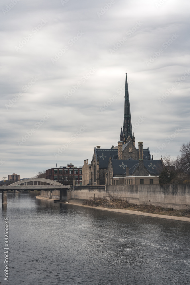 Old Historic Church beside a river with a bridge during cloudy weather