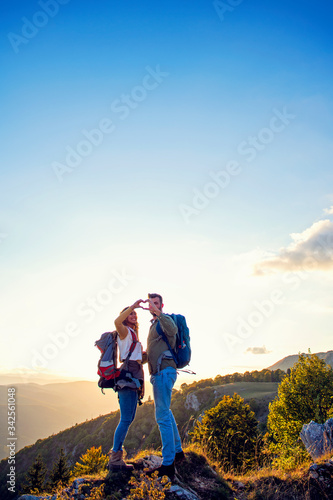 Hikers with backpacks relaxing on top of a mountain and enjoying the view of valley