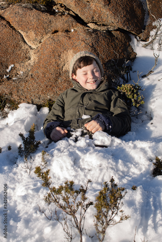 Young boy exploring and playing on a snow covered Mount Wellington