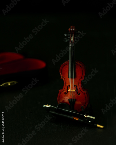  Violin miniature against black background  with a hint of the case in the background- the music will start soon 