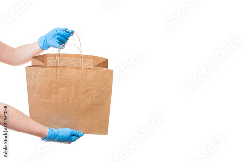 hands in sterile gloves of a courier for the safe delivery of goods in an eco friendly package shows a unlabel package without a logo isolated on a white background with copy space.