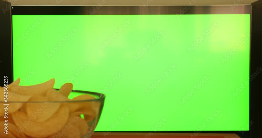 Female Hand Using A Remote Control To Channels On Flat Green Screen TV