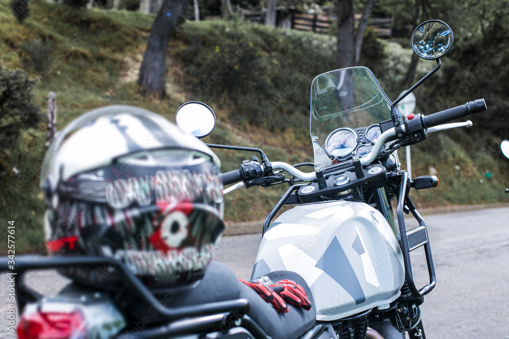 stopped motorcycle with an unfocused helmet on his saddle and a focused motorcycle body, handlebar and nature background stopped motorcycle with an unfocused helmet on his saddle and a focused motorcycle body, handlebar and nature background