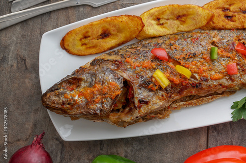 Grilled fish curry with plantain and salad. African national dish. Nigerian fish curry. Healthy lifestyle meal. Vegetarian food