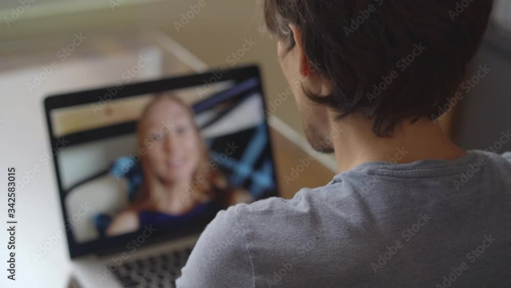 A man talks through video conferencing while he is sitting at home during the coronavirus self-isolation period. Social distancing concept A man talks through video conferencing while he is sitting at home during the coronavirus self-isolation period. Social distancing concept