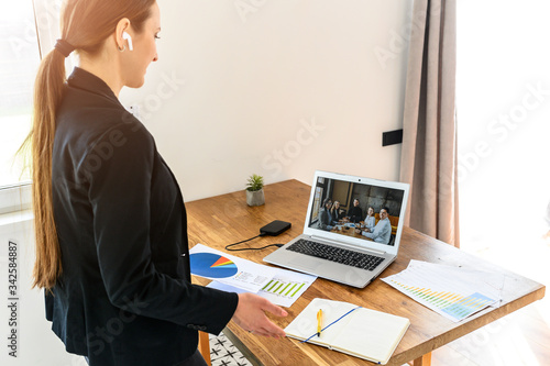 A woman works remotely, she watching at laptop webcam and talks via video with colleagues. Work at home concept