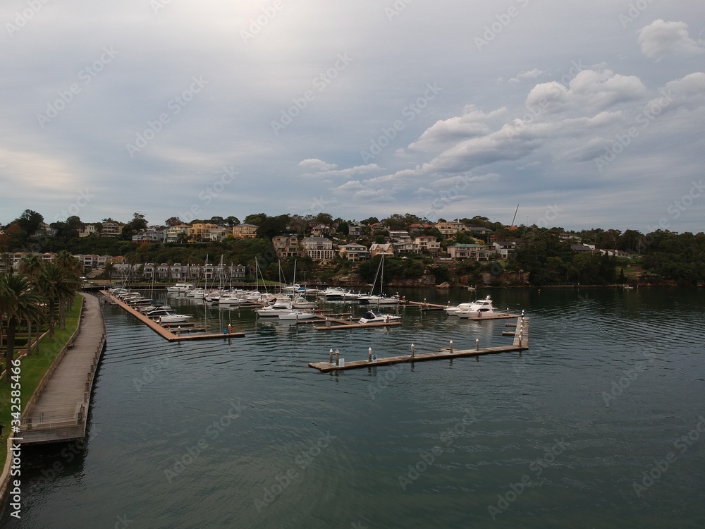 Fototapeta premium Panoramic drone aerial view over Sydney harbour on a cloudy sunset showing the nice colours of the harbour foreshore