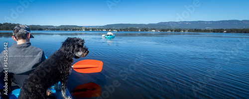 Panorama with teenage boy and dog kayaking on peaceful sunny lake, best friends, isolation calm and peace concept
