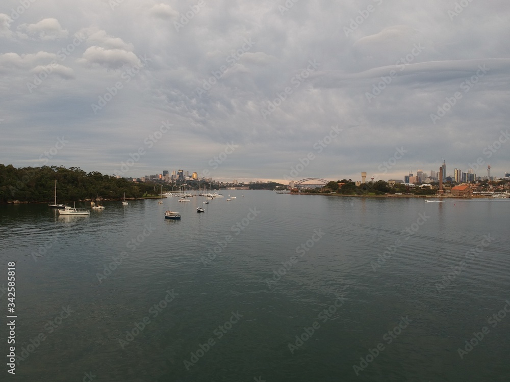 Panoramic drone aerial view over Sydney harbour on a cloudy sunset showing the nice colours of the harbour foreshore