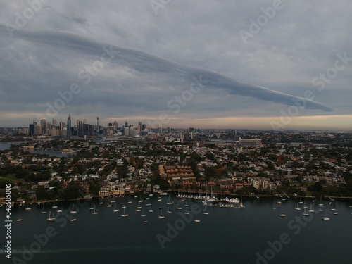 Panoramic drone aerial view over Sydney harbour on a cloudy sunset showing the nice colours of the harbour foreshore © Elias Bitar