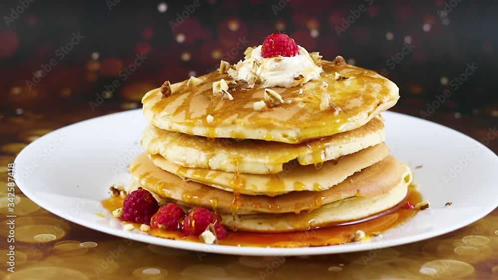 Pancakes on white plate decorated with maple syrup, raspberries and nuts on the top Pancakes on white plate decorated with maple syrup, raspberries and nuts on the top