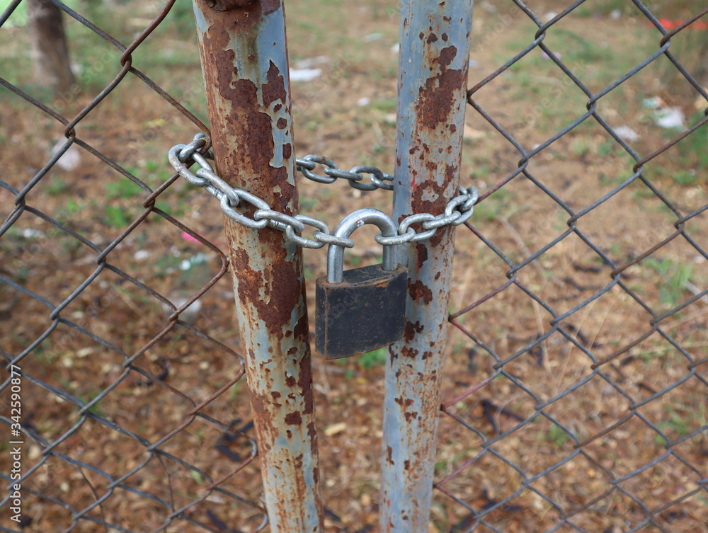 Close view of old padlocks and a chain on a rusty metallic fence. Close view of old padlocks and a chain on a rusty metallic fence.