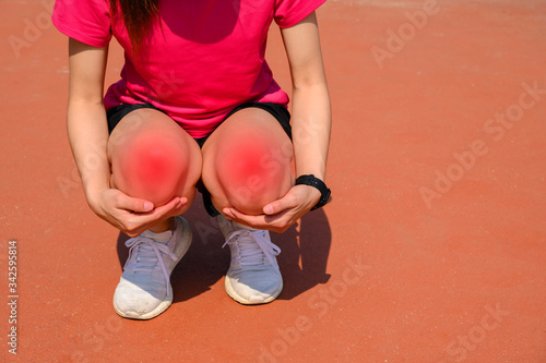 Cropped shot of woman runner kneel down, suffering from knee pain. It often happens when your kneecap is out of alignment. Conceptual of common running injuries.