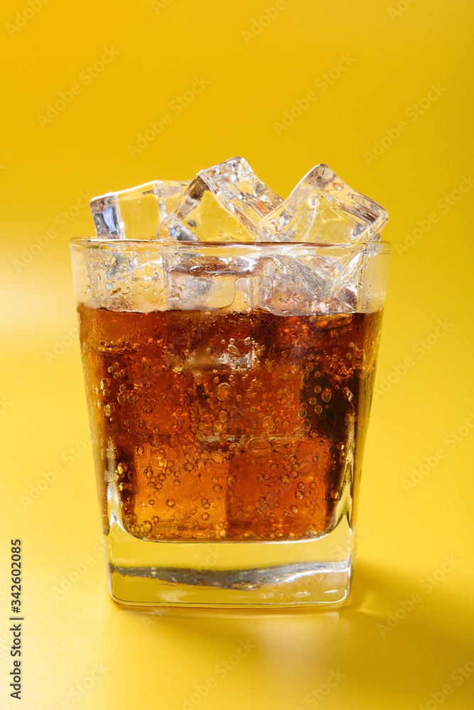 cup of iced cola on a yellow background cup of iced cola on a yellow background