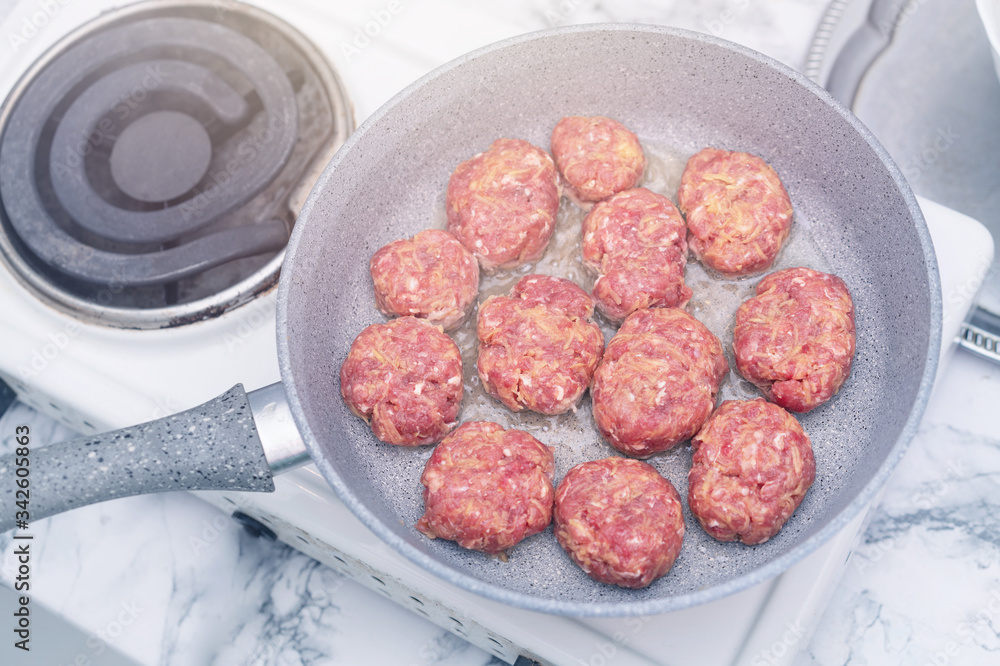 Cutlets of minced meat veal and pork are fried in a frying pan on an electric small stove close up Cutlets of minced meat veal and pork are fried in a frying pan on an electric small stove close up
