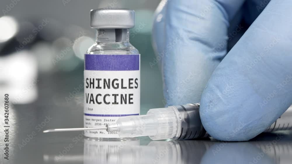 Shingles vaccine vial in medical lab with syringe placed next to it. Shingles vaccine vial in medical lab with syringe placed next to it.