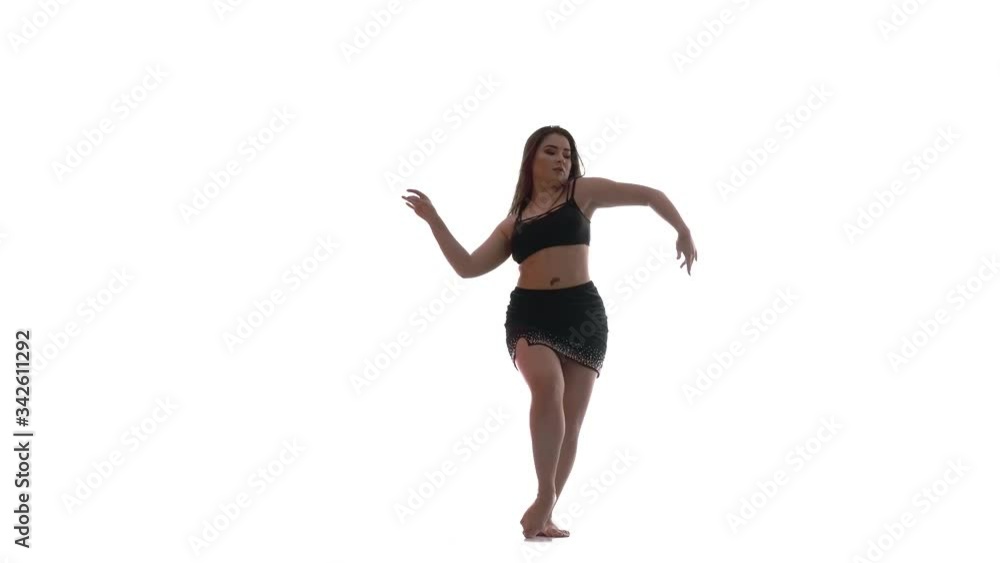 young beautiful girl with long hair and a beautiful plump figure in a black top and a short black skirt dances belly dance, oriental dance, exotic dance on a white background, isolated young beautiful girl with long hair and a beautiful plump figure in a black top and a short black skirt dances belly dance, oriental dance, exotic dance on a white background, isolated