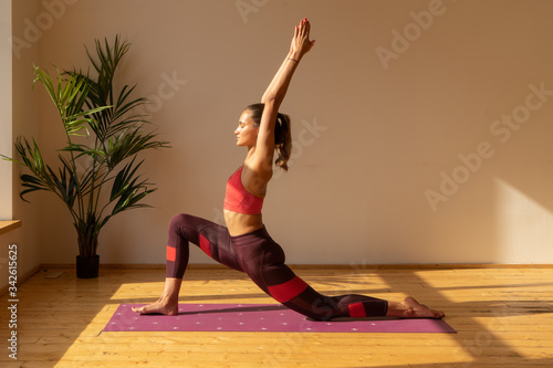 young woman doing yoga exercise on yoga mat at home near window