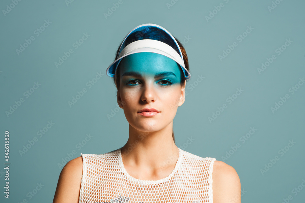 attractive young woman with sunvisor isolated on blue background, close up attractive young woman with sunvisor isolated on blue background, close up