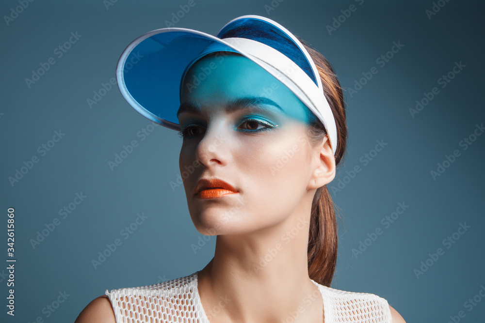 attractive fashion woman with sunvisor isolated on blue background, close up portrait attractive fashion woman with sunvisor isolated on blue background, close up portrait