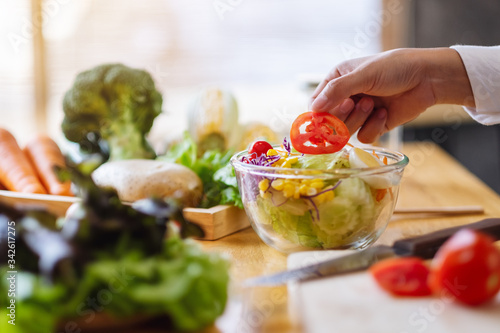 Closeup image of a female chef cooking a fresh mixed vegetables salad in kitchen