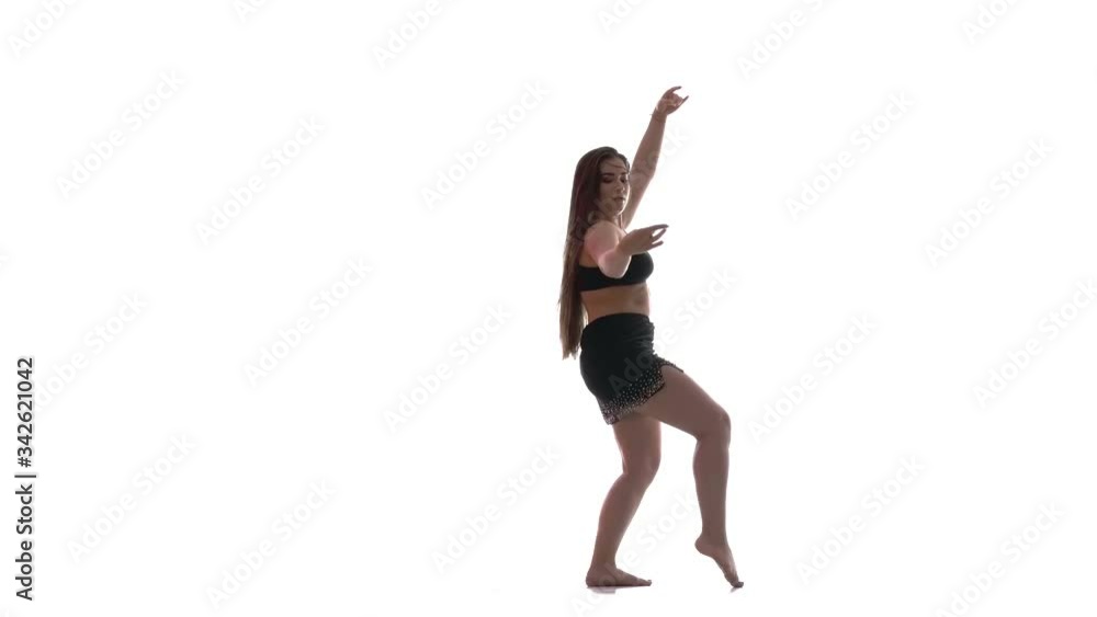 young beautiful girl with long hair and a beautiful plump figure in a black top and a short black skirt dances belly dance, oriental dance, exotic dance on a white background, isolated young beautiful girl with long hair and a beautiful plump figure in a black top and a short black skirt dances belly dance, oriental dance, exotic dance on a white background, isolated