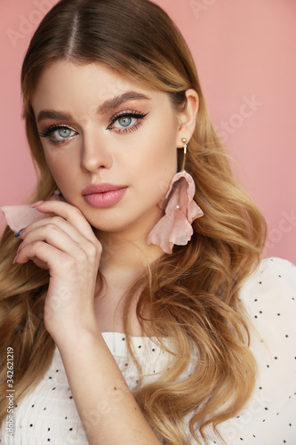 beautiful young woman with blond natural hair and light makeup posing at studio