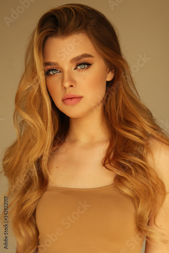 beautiful young woman with blond natural hair and light makeup posing at studio