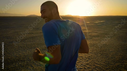 Athletic man working out with battle ropes on a dry lake at sunset photo