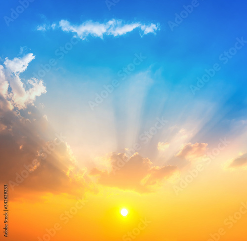 bright sun with orange and yellow light on blue sky with clouds