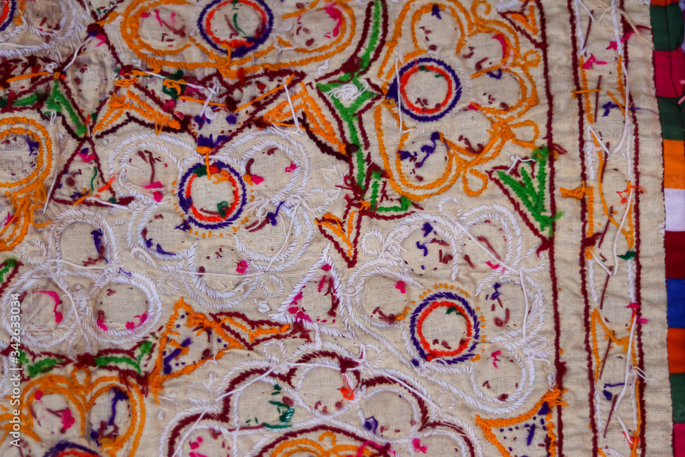 hand embroidered cross on the canvas. Wooden table and thread stranded cotton on the background, india embroidery handicrafts close-up view