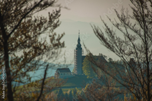 Small picturesque church in Crni Vrh, Slovenia, during early morning hours at sunrise. The bell tower is just being renovated as it has metal scaffolding around it.