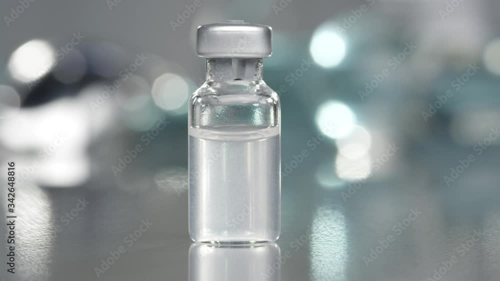 Vial filled with liquid vaccine in medical lab slowly rotating around. Vial filled with liquid vaccine in medical lab slowly rotating around.