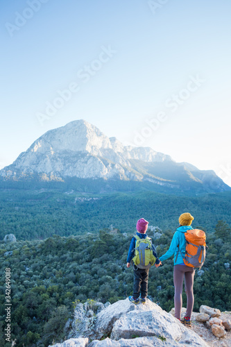 The boy and his mother are standing on the top of the mountain.