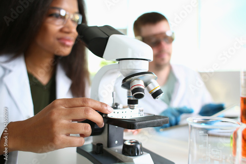Two scientists of a student chemist are conducting research using microscope for bacterial contamination of water to search for vaccine to treat diseases in medicine