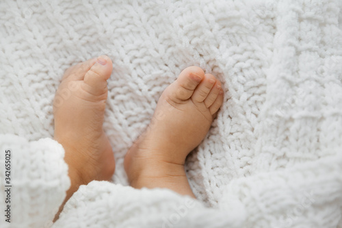 Top view of tiny baby girl feet on white blanket as a background, closeup of infant legs