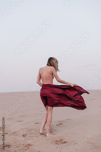 A girl with a fabric is standing in the wind in the desert photo