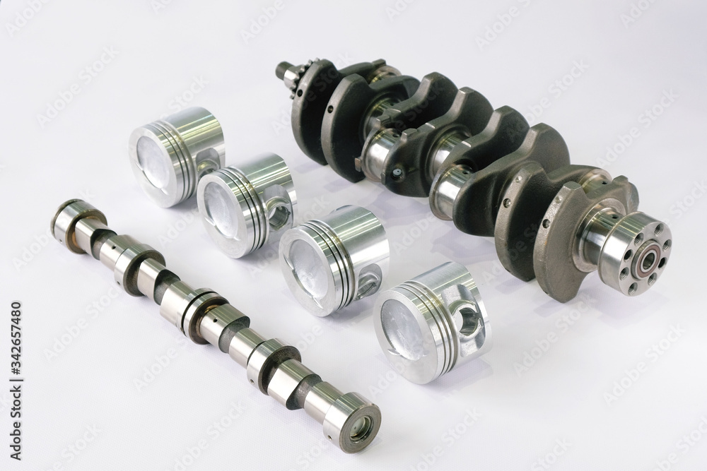 Spare parts for the car engine. Crankshaft with sprocket Assembly, camshaft and pistons complete on white background, top view. Spare parts for the car engine. Crankshaft with sprocket Assembly, camshaft and pistons complete on white background, top view.