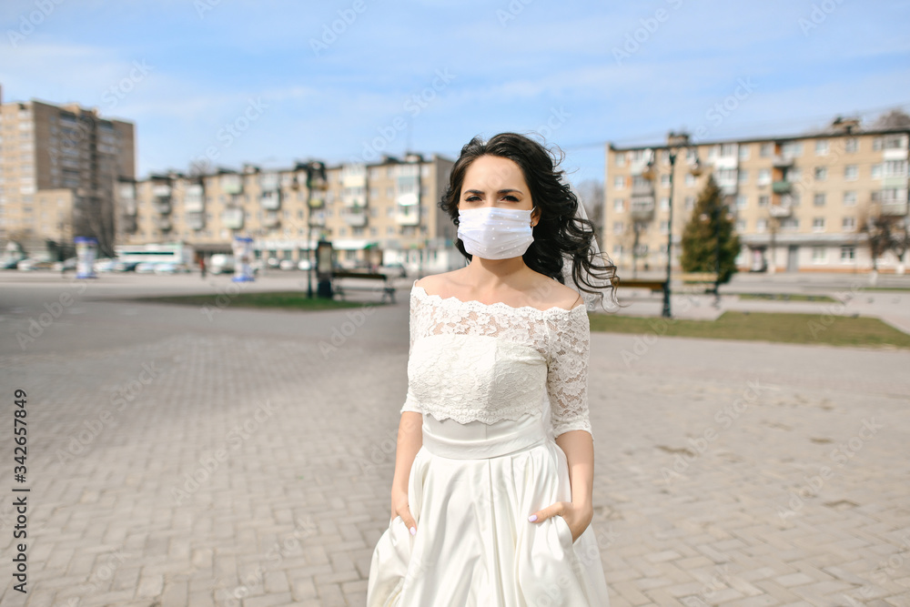 Bride in medical mask on street of city during coronavirus epidemic. Wedding day COVID-19 protection Bride in medical mask on street of city during coronavirus epidemic. Wedding day COVID-19 protection