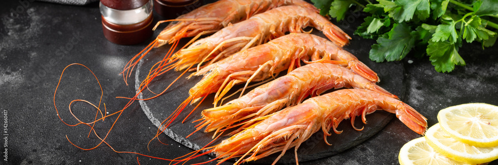 Large langoustines on a black plate on the black kitchen table. Seafood for a healthy diet. Banner Large langoustines on a black plate on the black kitchen table. Seafood for a healthy diet. Banner