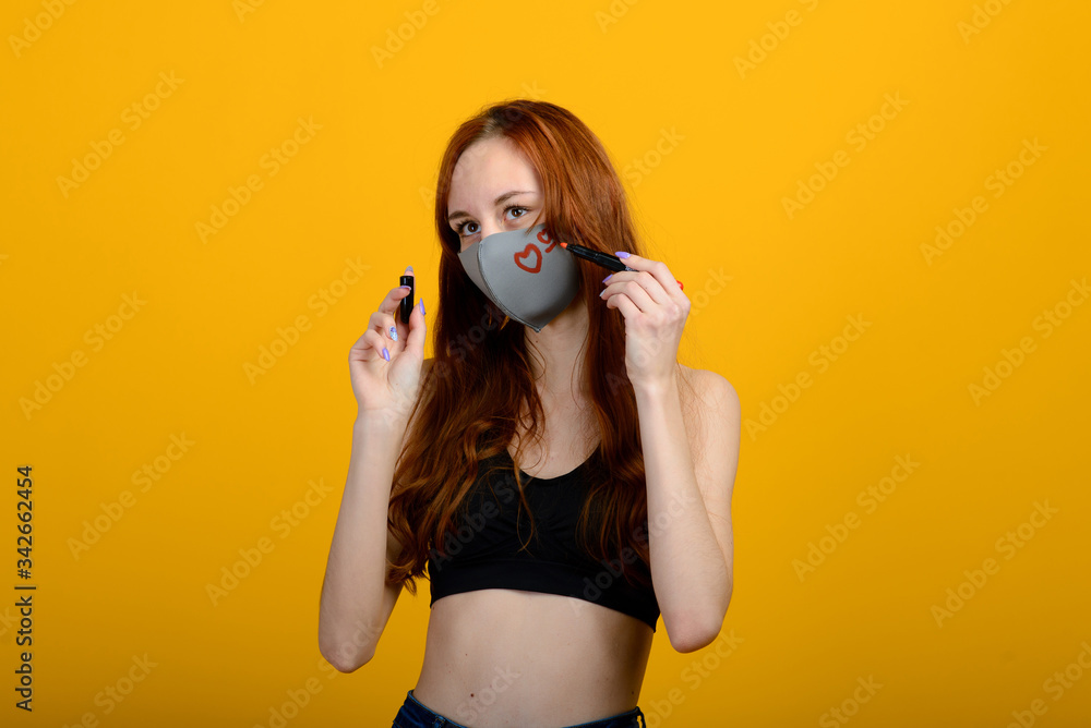 Obraz premium Portrait of a girl in a mask, which puts on a rubber glove. Yellow background.
