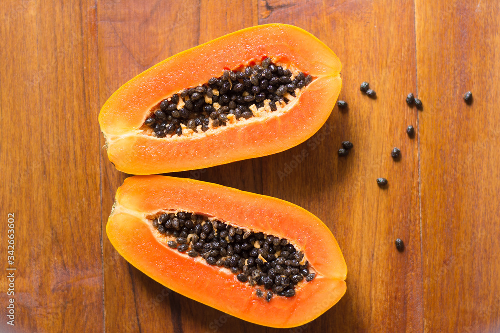 Papaya fruit on wooden background.Slices of sweet papaya on wooden background,Halved papayas Papaya fruit on wooden background.Slices of sweet papaya on wooden background,Halved papayas