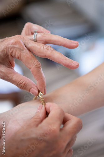 Mother placing bracelet on her daughters wrist for her wedding day